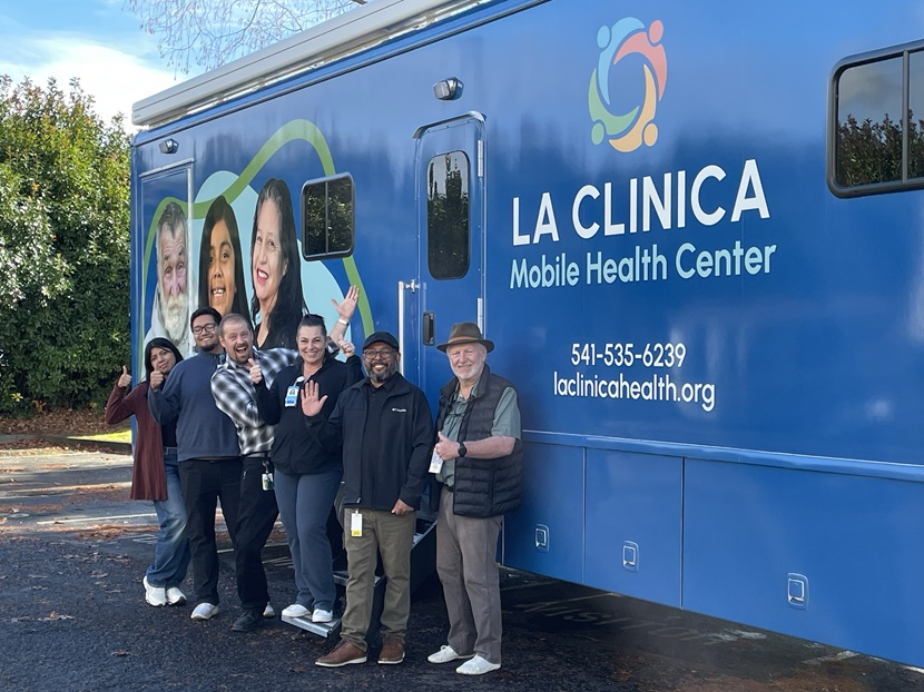 JCC grants story-image 2-La Clinica mobile health center La Clinica mobile health team (smiling and waving) gathers in front of blue mobile clinic at outreach event.