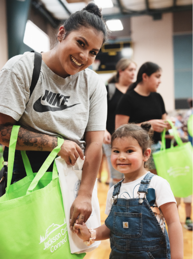 A mother holds hands with her young daughter as they gather school supplies.